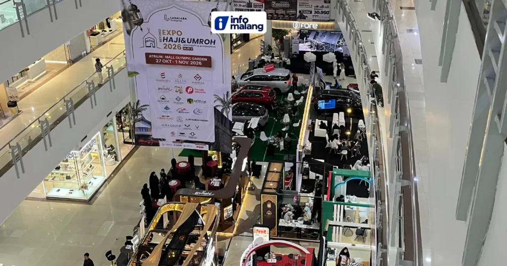 Suasana pameran Beyond Expo Haji & Umroh 2026 di atrium Mall Olympic Garden Malang dilihat dari lantai atas, dengan booth biro perjalanan, deretan mobil, dan spanduk acara bertanggal 27 Oktober–1 November 2026.